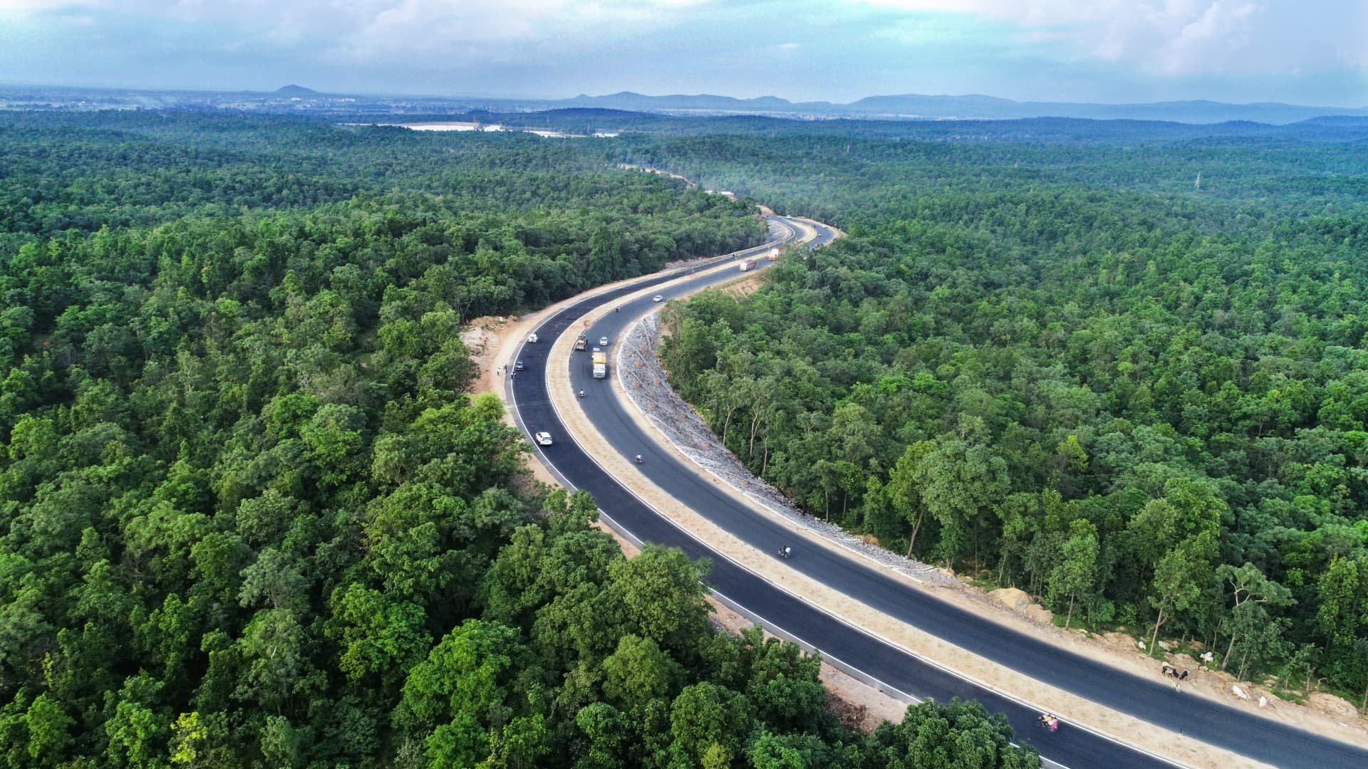 Aerial view of a highway curving through dense forest